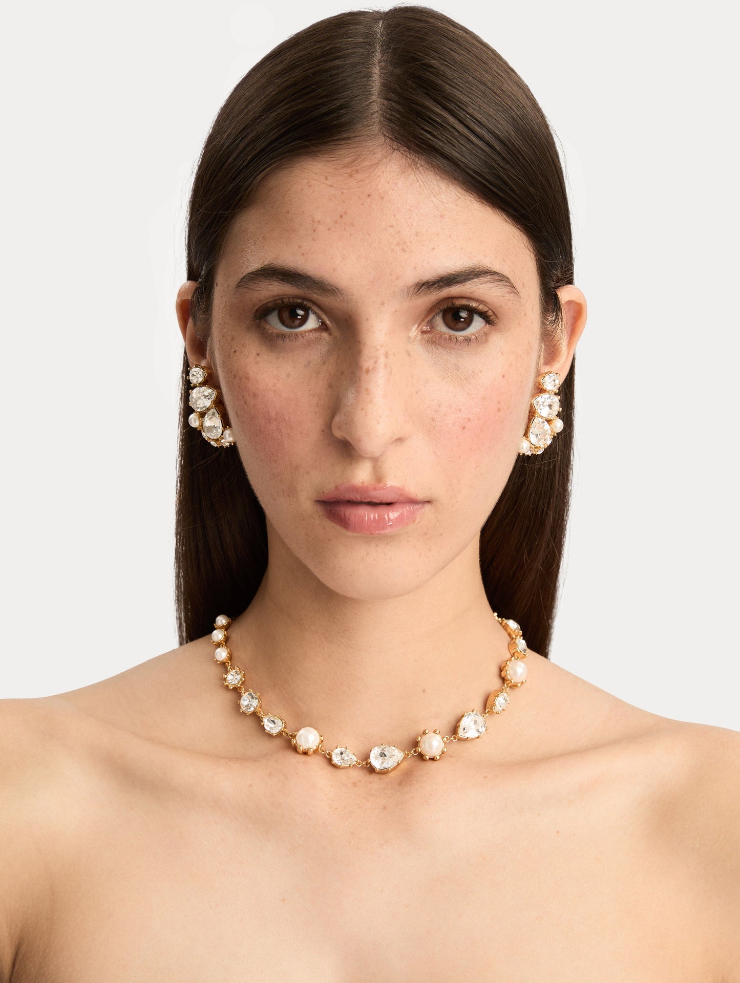 Gold Faceted Crystal Necklace featuring alternating white pearls and clear crystal settings in a graduated design. Front View.
